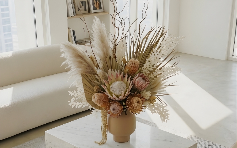 Dried flower arrangement with pampas grass and protea displayed on a marble coffee table in a modern UAE living room.