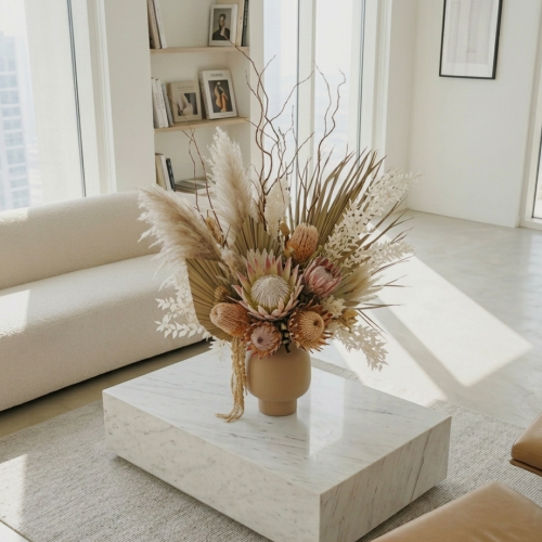 Dried flower arrangement with pampas grass and protea styled on a marble coffee table in a modern living room.